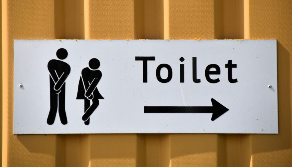 Image of washroom sign where the man and woman are both trying to hold it in and avoid peeing before they get to the washroom