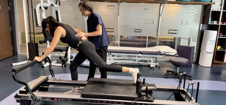 Vancouver physiotherapist Winnie Chan gives guidance to patient doing clinical pilates at Cross Roads Physiotherapy & Massage Therapy clinic